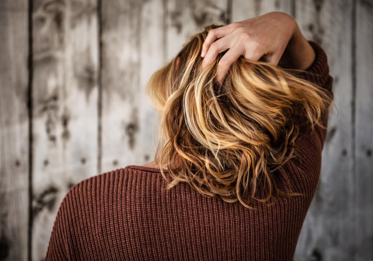 mulher loira passando a mão no cabelo