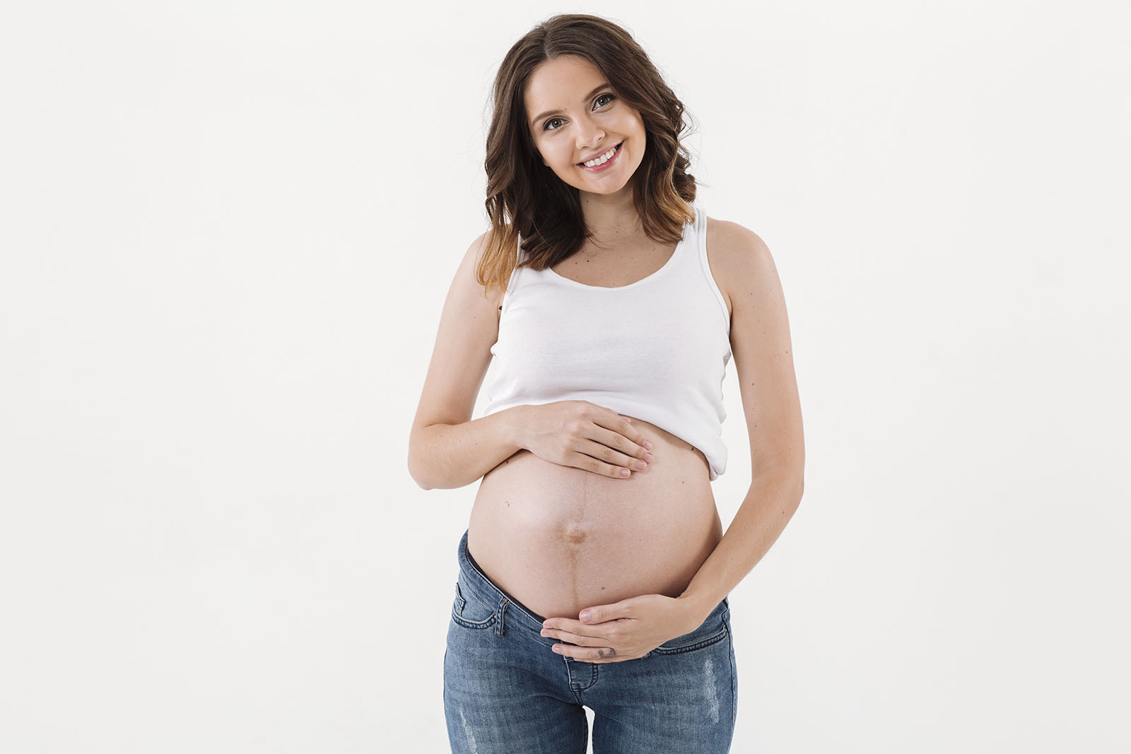 Mulher gravida com roupas casuais e as mãos na barriga em um fundo branco