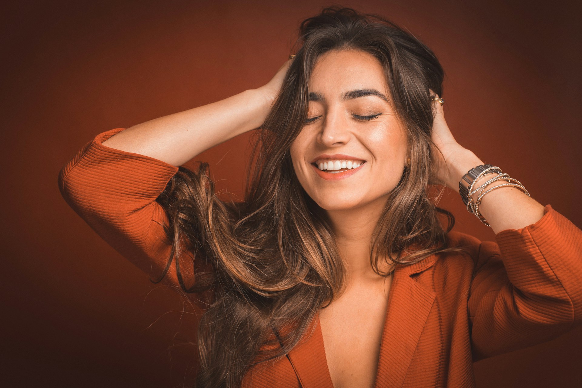 Mulher sorrindo com cabelo solto em fundo laranja
